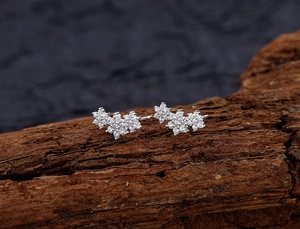 Detailed view of silver snowflake earrings with cubic zirconia on rustic bark texture