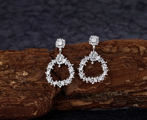 Macro detail of S925 sterling silver drop earrings with pavé white zircons on wood