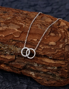 Détail du collier à double anneau entrelacé avec micro-pavage de diamants sur chaîne argent