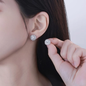 Elegante silberne Blumen-Ohrstecker mit funkelnden Kristallen am Ohr getragen