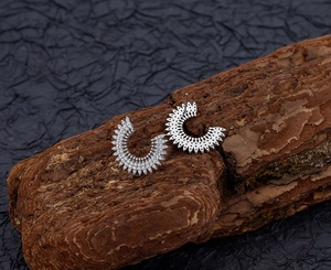 Dettaglio macro degli orecchini a girasole con zirconi scintillanti su superficie in corteccia