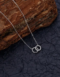 Gros plan d'un collier à cercles entrelacés avec des pierres étincelantes sur écorce