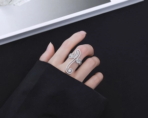 Close-up of S925 silver swirl ring with pavé-set zircons worn by a model in high contrast