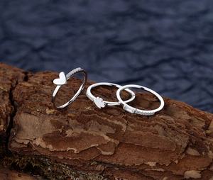 Macro detail of three-piece 925 silver rings with heart and zircon on rustic bark