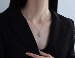 Detail of starburst pendant necklace with zircons on model wearing black blazer