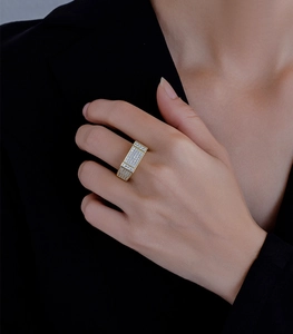 Gros plan d'une bague large plaquée or sertie de cristaux sur manche de costume noir