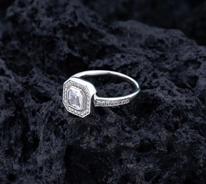 Macro shot of silver S925 ring with emerald-cut main stone and micro-pave diamonds