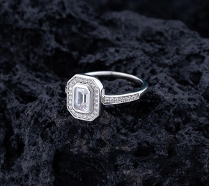 Macro shot of S925 silver ring with emerald cut center stone on black lava rock