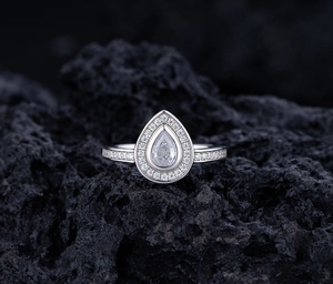 Macro detail of teardrop S925 silver ring with halo diamonds on volcanic rock base