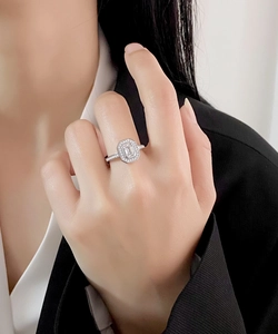 Close-up of a silver S925 emerald-cut ring with halo micro-pave diamonds on a hand
