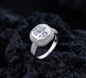 Vue macro d'une bague en argent S925 avec diamant carré sur roche volcanique noire
