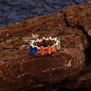 Rainbow baguette-cut zircon eternity ring in gold finish on natural bark display