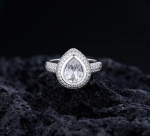 Vue macro d'une bague en argent avec pierre poire sur une roche volcanique noire