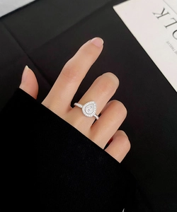Macro shot of S925 silver pear-shaped halo ring with pavé-set diamonds on a model hand