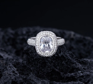 Macro shot of S925 silver halo ring with cushion-cut zircon on dark volcanic rock