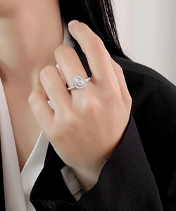 Macro detail of teardrop pear-cut halo ring with micro-paved diamonds on silver band