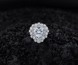 Detailed macro view of heart-shaped diamond ring with halo pavé setting on dark stone