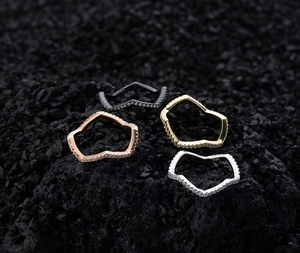 Macro shot of four stacked lightning-shaped rings with 925 silver stamp on dark stone