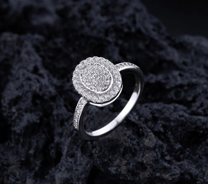 Macro side view of an oval double-layer pavé cluster ring on a dark volcanic rock