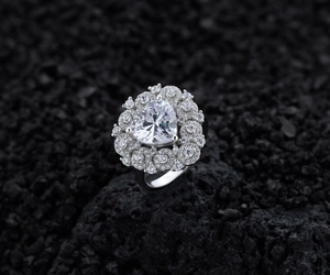 Macro shot of heart-cut diamond ring with pavé setting on dark volcanic stone