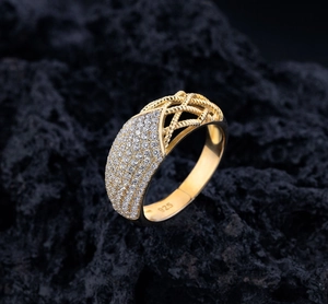 Macro shot of 925 silver ring with pavé diamonds, gold finish and woven hollow design