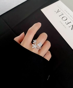 Close-up of silver adjustable ring featuring crystal floral petals and butterfly