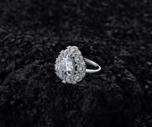 Macro shot of silver pear-cut diamond ring on dark volcanic stone backdrop