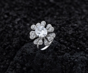 Primo piano dell'anello a fiore con diamante ovale su uno sfondo di pietra scura