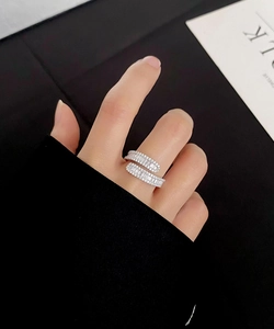 Detail of silver crisscross S925 ring with baguette zircon stones on a female model finger
