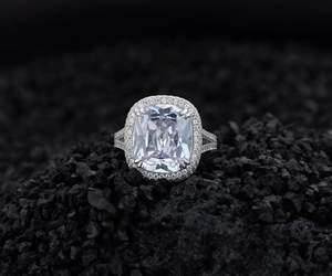 Détail macro d'une bague halo à coupe coussin sur un fond de roche volcanique noire