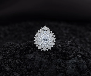 Macro detail of pear-cut crystal centerpiece with floral halo stones on silver ring