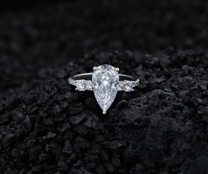 Macro shot of a pear-cut diamond ring on dark volcanic stone showing intricate details