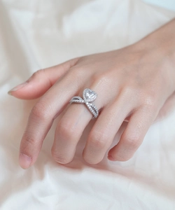 Détail d'une bague en diamant coeur sur main avec anneau élégant en argent torsadé