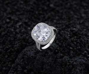 Détail macro d'une bague de fiançailles halo avec taille coussin et diamants pavés sur roche