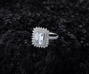 Macro detail of emerald cut gemstone ring with double halo diamond setting on black stone