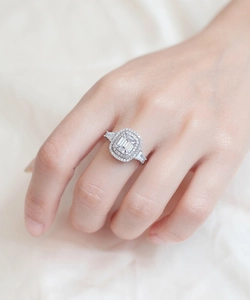 Macro shot of 925 silver halo ring with emerald cut center stone worn on finger