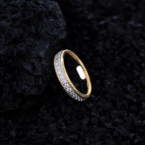 Elegant gold twisted edge ring with sparkling pavé stones on dark charcoal background