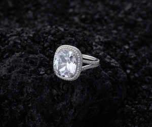 Gros plan d'une bague en argent taille coussin avec double halo et anneau fendu