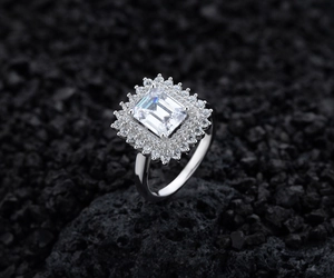 Macro side view of emerald-cut diamond ring with pavé double halo on black volcanic stone