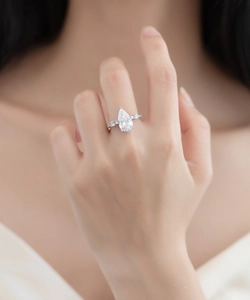 Detailed view of pear-cut diamond ring on finger with sterling silver and small side stones