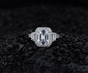 Macro detail of emerald cut halo silver ring with rectangle side diamonds on black stone