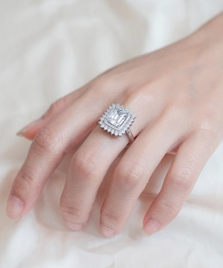 Close-up of elegant emerald cut diamond ring with double halo setting on a model's hand