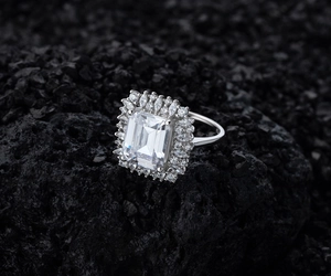 Macro shot of silver ring featuring an emerald-cut centerpiece with a sparkling halo