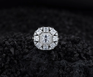 Macro shot of emerald-cut stone cluster ring on black volcanic stone background