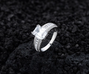 Macro d'une bague en argent 925 avec zircon taille émeraude sur roche volcanique noire