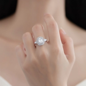 Luxurious emerald cut ring with double halo and baguette side stones on model hand