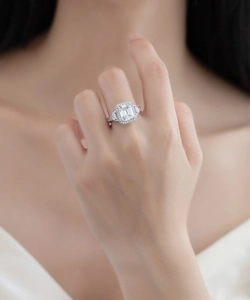 Macro detail of emerald cut halo silver ring with side baguette diamonds on hand