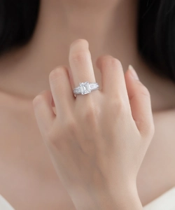 Gros plan d'une bague en argent avec pierre taille émeraude et pavage