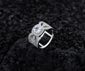 Macro shot of silver ring with square diamond and intricate hollow heart side details