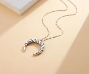 Détail macro du collier croissant de lune avec texture torsadée et zircons cubiques